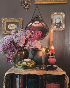 a table topped with vases filled with flowers next to a mirror and framed pictures