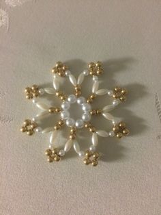 a white and gold brooch sitting on top of a piece of cloth covered in beads