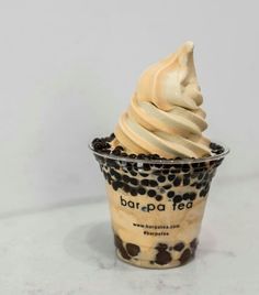 an ice cream sundae with chocolate chips and whipped cream in a plastic cup on a marble surface