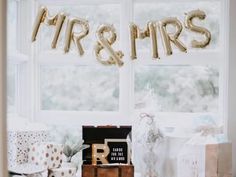 a room filled with lots of presents under a balloon that says mr and mrs on it