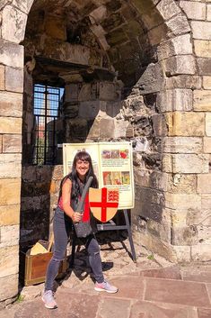 a woman standing in front of an arch with a shield on it's chest