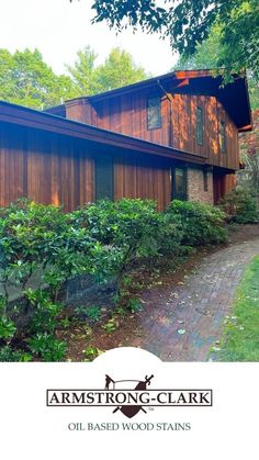 the exterior of an old - fashioned wooden house with trees and shrubs surrounding it in front of a brick walkway