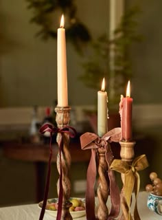 two candles are sitting on a table next to some other items with ribbons around them