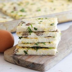 four pieces of food sitting on top of a wooden cutting board next to an egg