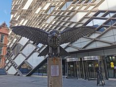 a statue of an eagle is in front of a building with glass walls and windows