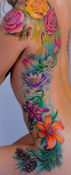 a woman's back with flowers and pine cones on the bottom part of her body