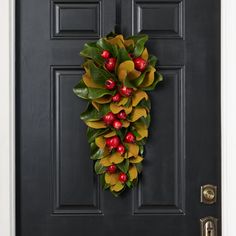 a black front door with a wreath on it and holly leaves hanging from the side