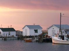 the boats are docked in the water by the houses on the other side of the dock