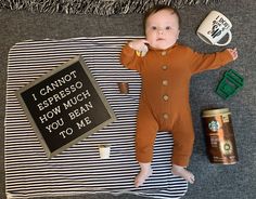 a baby laying on top of a blanket next to a can of coffee