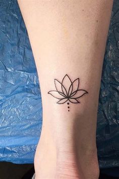 a lotus tattoo on the ankle is shown in black ink and has a small dot at the center