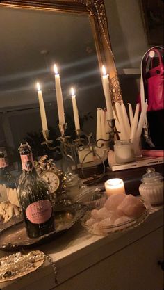 a table with candles, bottles and other items on it in front of a mirror