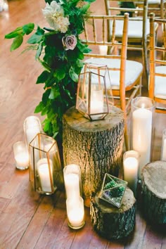 a table with candles and some flowers on top of it next to a tree stump