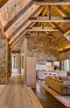 a living room filled with furniture next to a stone wall covered in wood planks