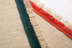 three different colored pieces of fabric on top of each other with orange and green fringes