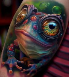 a colorful frog tattoo on the arm with bubbles and an eyeball in it's center