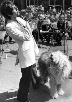 a man in a suit playing trumpet with a dog standing next to him