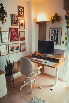 a desk with a computer on top of it in front of a wall full of pictures