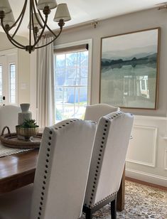 a dining room table with white chairs and a chandelier