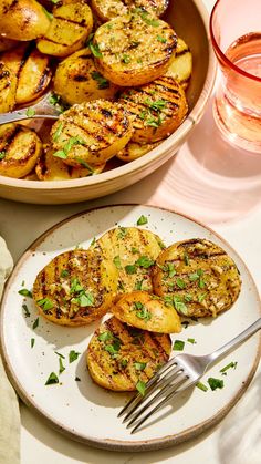 grilled potatoes on a plate with a fork and glass of water next to it