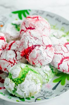 a white plate topped with red and green crinkle cookies covered in powdered sugar