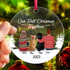 someone holding up a christmas ornament with two dogs