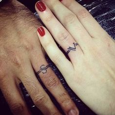 two people with matching wedding rings on their fingers, one has a cross and the other has a heart