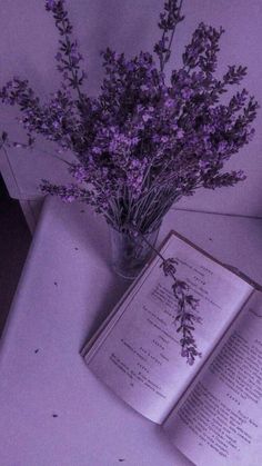 an open book sitting on top of a table next to a vase filled with flowers