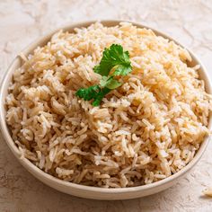 a white bowl filled with rice and garnished with parsley