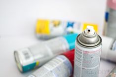 several cans of spray paint sitting next to each other on a white counter top,