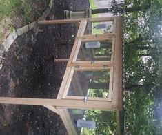 a bird cage is sitting on top of a wooden platform in the middle of a yard