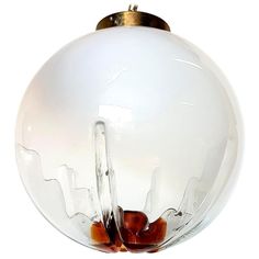 a glass ball hanging from a chain on a white wall