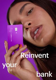 a woman holding a purple bank card with the words reinvent your bank on it