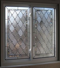 two stained glass windows sitting next to each other in a window sill on the side of a wall