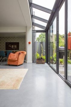 an orange chair sitting in the middle of a living room next to a glass wall