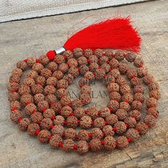 a red tasseled beaded necklace on top of a piece of wood