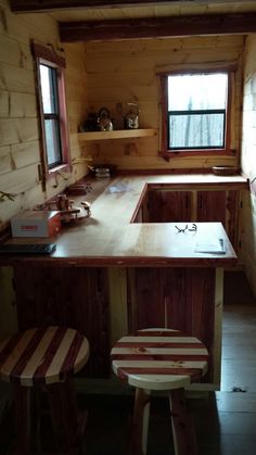 a small kitchen with an island and stools next to the counter top in a log cabin