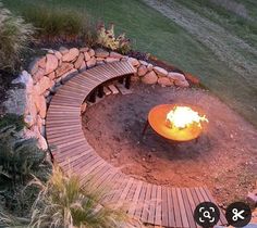 an outdoor fire pit surrounded by rocks and grass