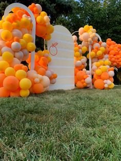 there are many balloons in the shape of letters and numbers on this lawn area that is decorated with orange, yellow and white balls