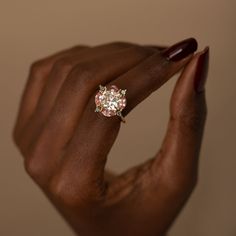 a woman's hand with a ring on it and a pink diamond in the middle