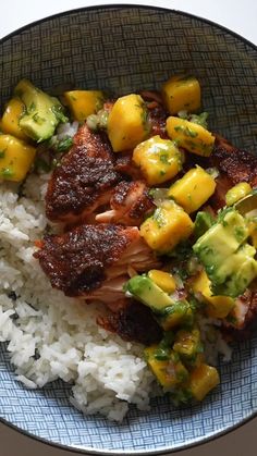 a bowl filled with rice and meat covered in pineapple salsa next to broccoli