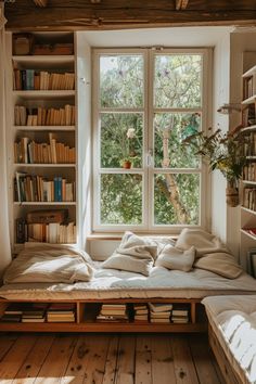 a bed sitting under a window next to a book shelf filled with lots of books