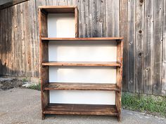 an old wooden bookcase sitting in front of a barn