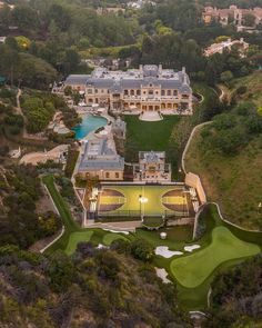 an aerial view of a large mansion with a golf course in the foreground and several trees surrounding it