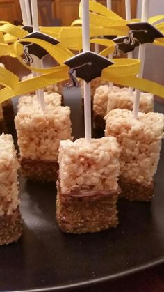 rice krispy treats are arranged on a black plate with yellow streamers and forks