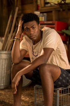 a young man sitting on top of a metal chair next to a wire basket filled with items