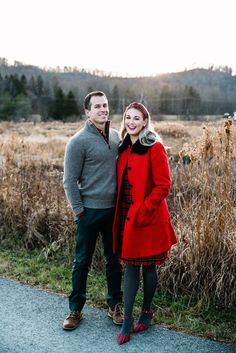 a man and woman standing next to each other in front of tall grass with trees