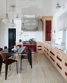 a kitchen with wooden floors and red cabinetry, along with white walls that matches the ceiling