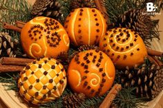 some oranges and cinnamon sticks are on a plate with pine cones, cinnamon sticks, and other decorations