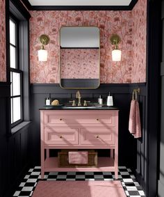 a bathroom with pink and black walls, checkered flooring and a gold framed mirror