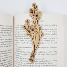 an open book with flowers cut out of it's pages and on top of the page is a piece of wood